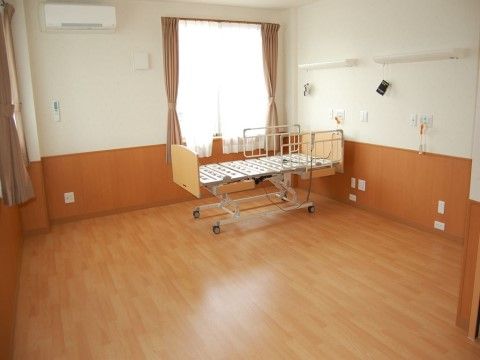 ベッドが一台置いてあり床や壁の一部が木調で温かみのある居室