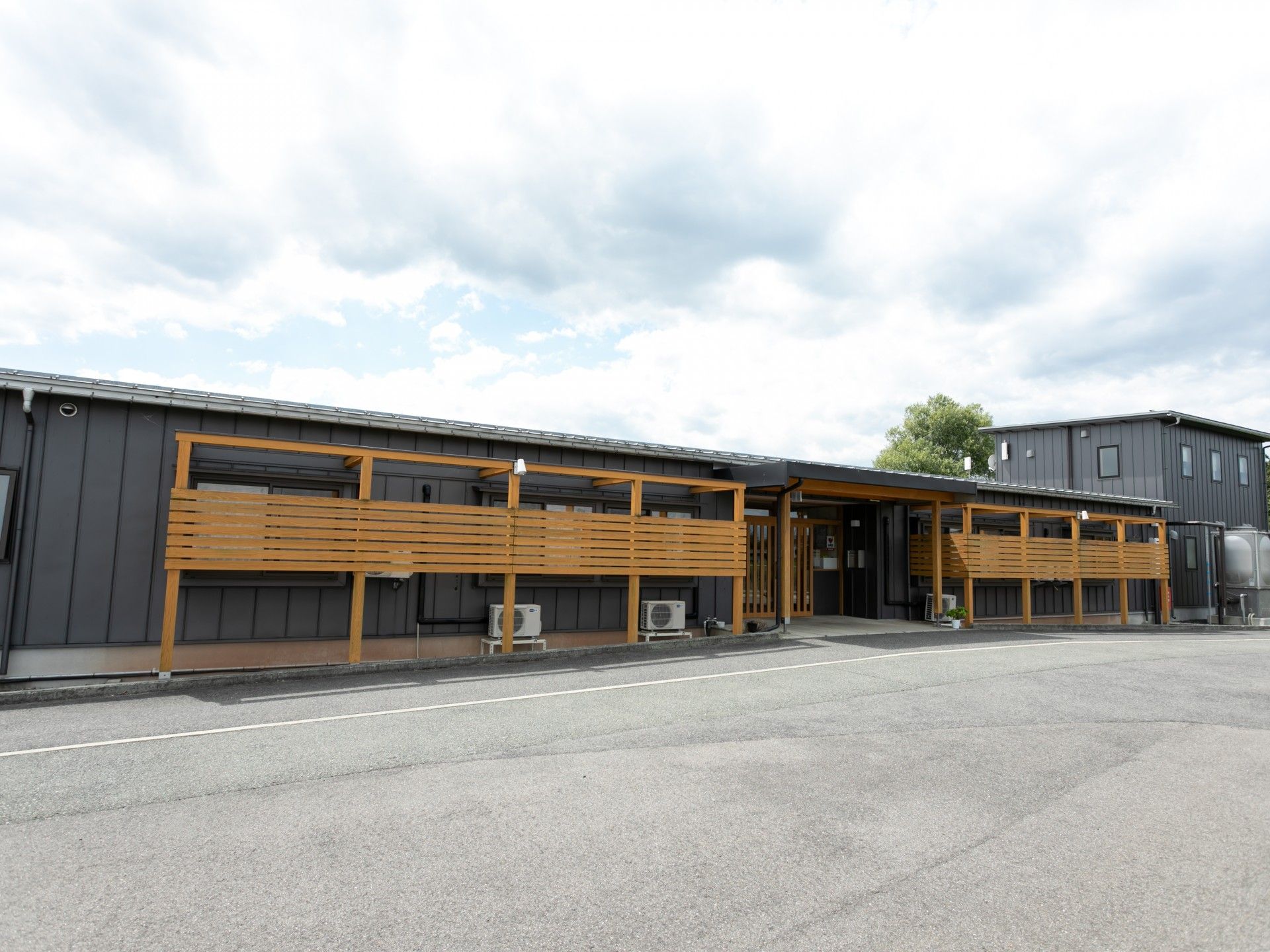 木陰にいる車椅子に乗った高齢男性と付き添う女性ヘルパー