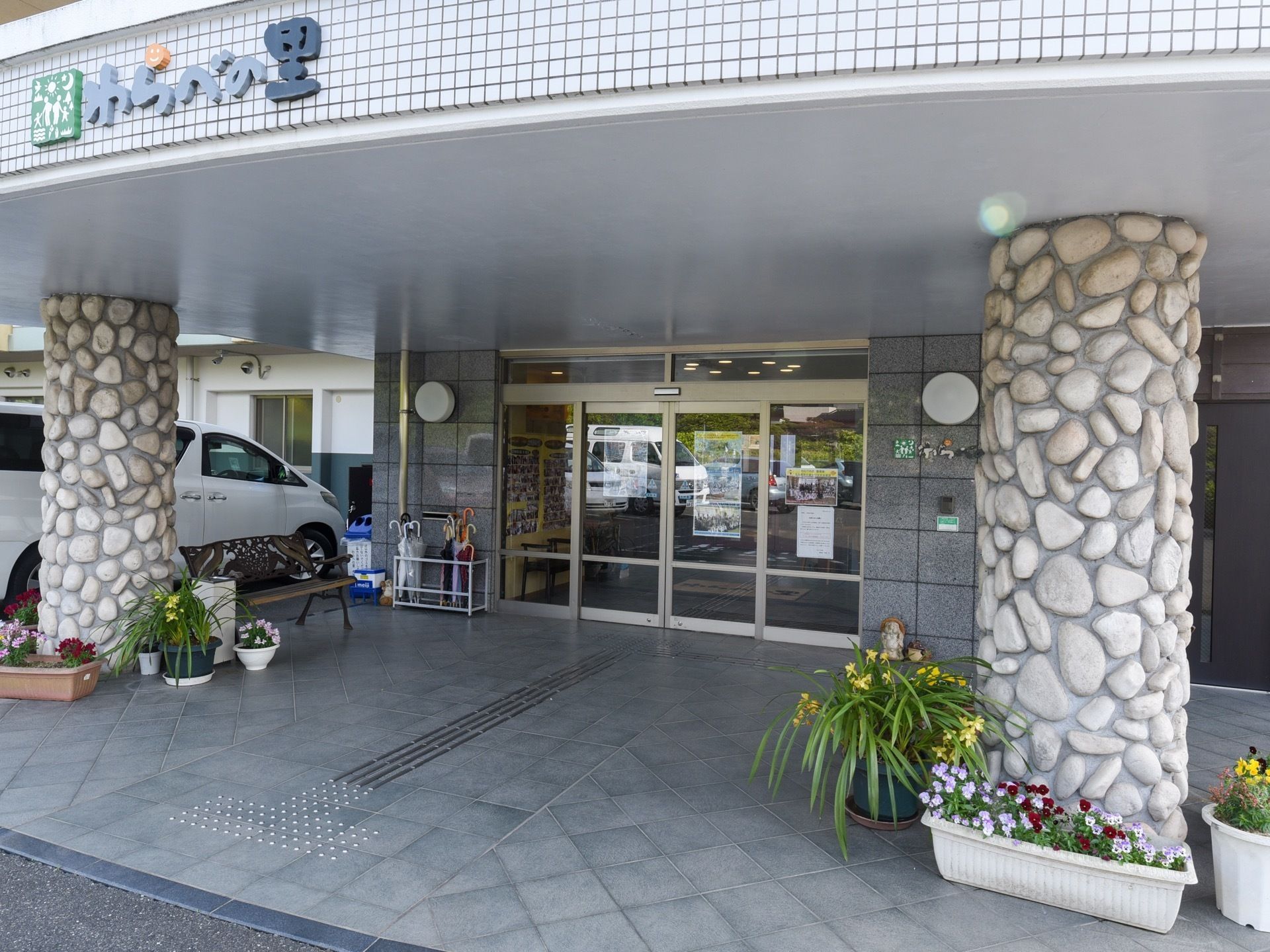 入口には両側が開閉する自動ドアが採用されている。入口の上部は屋根で覆われており、左右の柱の周囲には草花が植えられている。