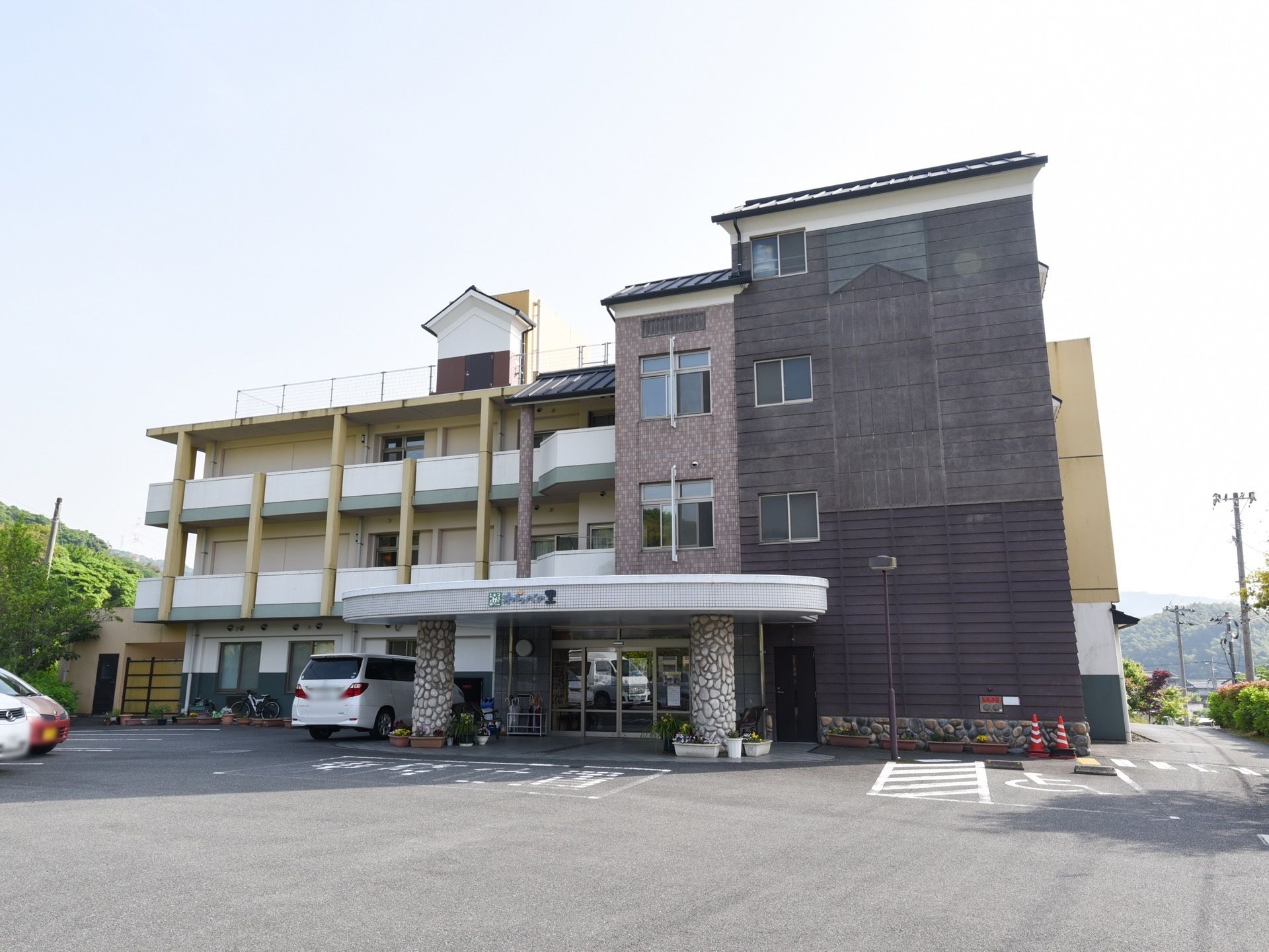 前方の両側に大きな柱を設置し、屋根を設けた玄関は、どっしりとした印象である。建物のすぐ傍には、車椅子専用の駐車スペースも備えている。
