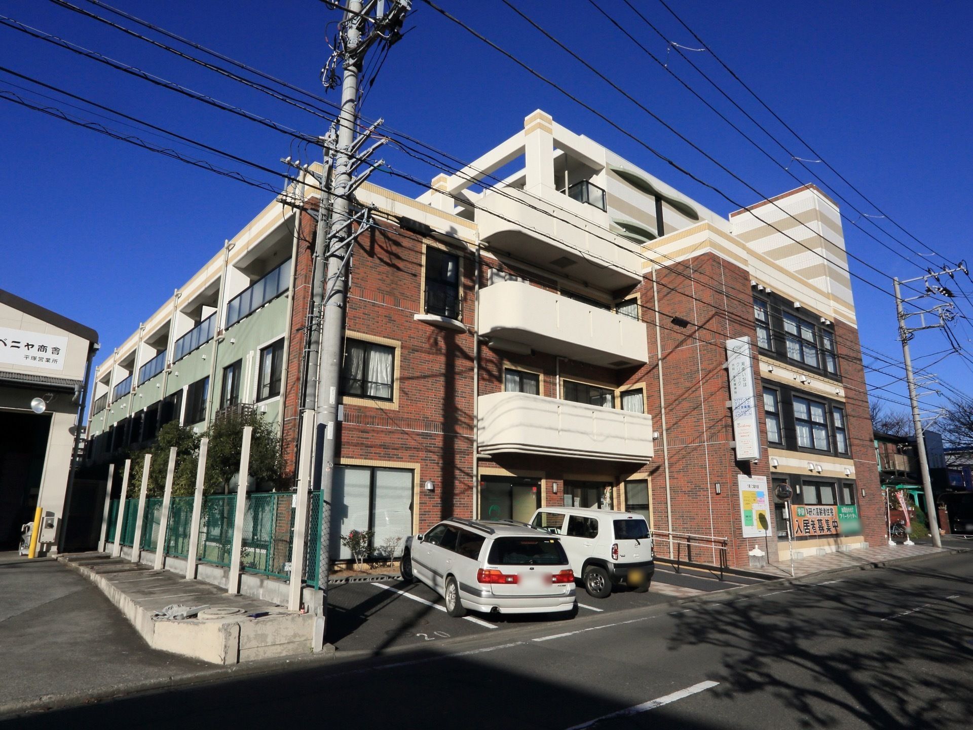 レンガ色の大きな建物の玄関までは、手すり付きのスロープで行けるようになっていて、その横には３台分の駐車場がある。