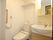 白を基調とした明るく清潔感があるトイレには収納スペース付きの機能的な洗面台が置かれている。壁には手すりと緊急通報装置設置されている。