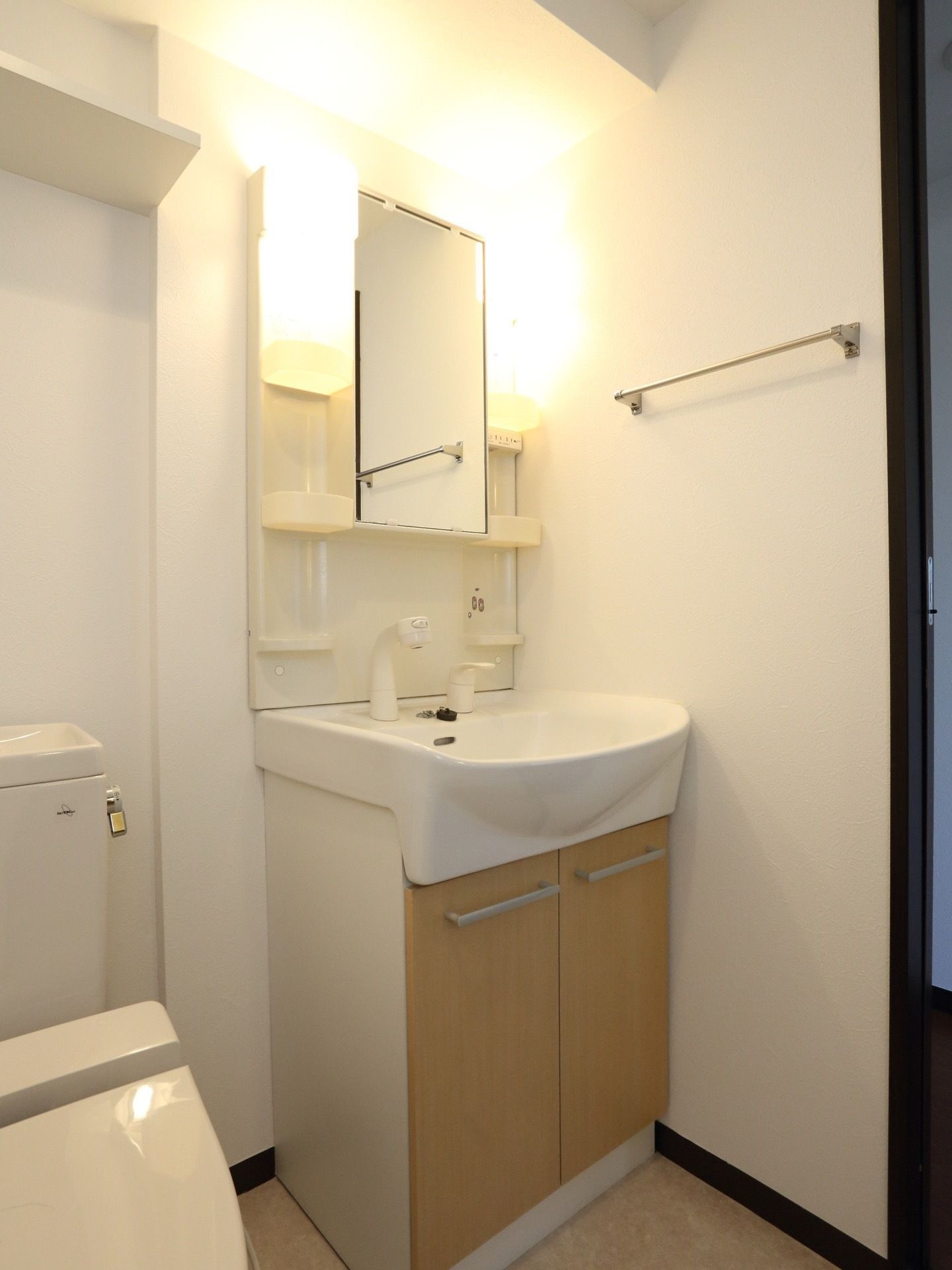居室のトイレ横にある洗面台の正面に鏡と照明が付いている。鏡の横と洗面台下には、収納が設けられている。