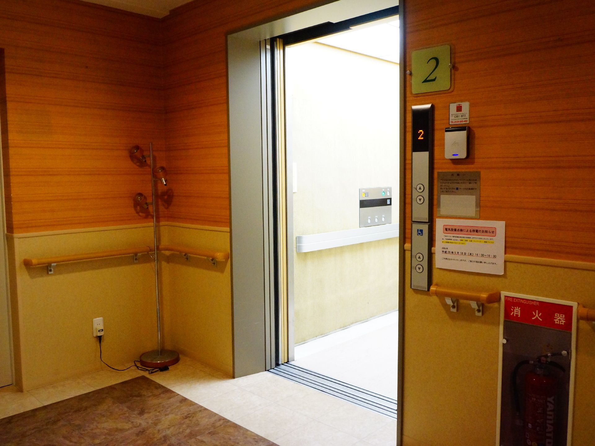 昇降口そばに手すりが設置してあるエレベーターで乗り降りが薬。車いす専用のボタンが設置してあるエレベーターなので、開閉時間を長くできる。