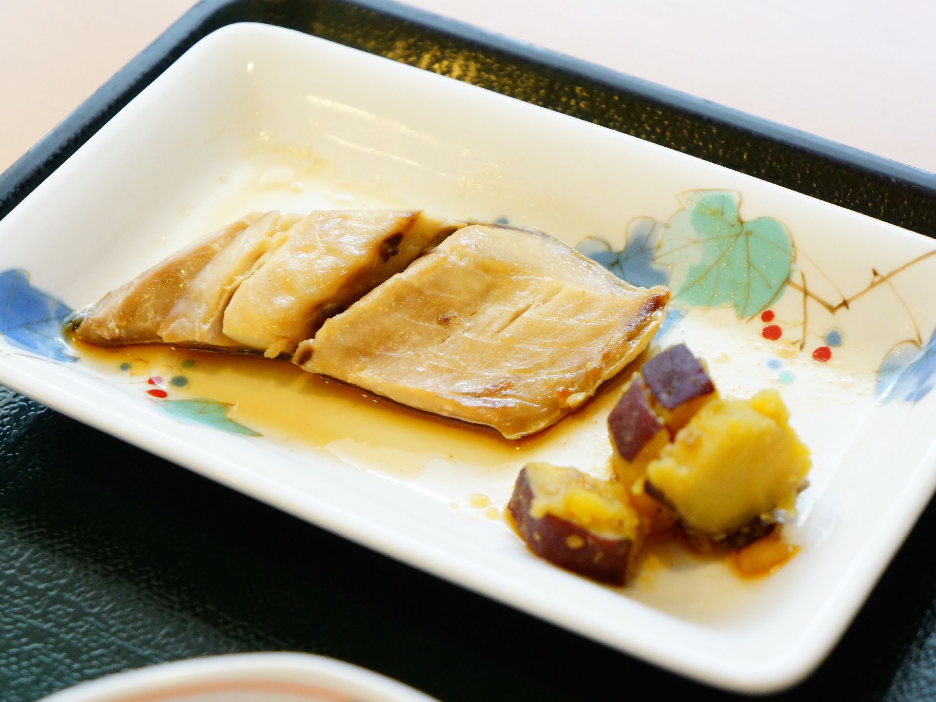 食事の一品がカメラに収めてある。煮魚とサツマイモの煮つけが四角い絵皿に盛り付けてあり、お盆の上に載っている。