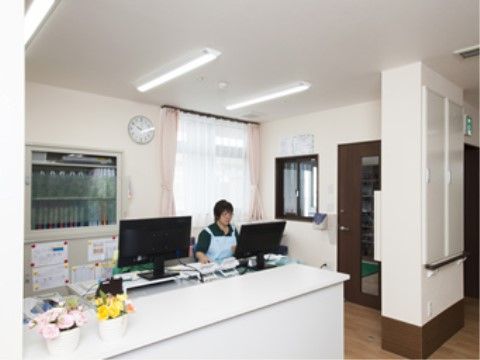 女性が座って作業しているカウンターの向こうの事務所
