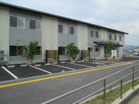 白とグレーを基調とした２階建てのモダンな外観。建物の前に駐車場があるので来訪者様などに便利に使っていただける。