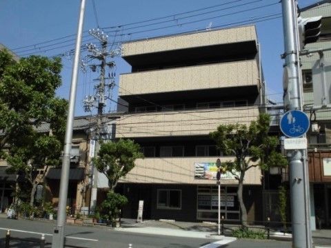 街路樹のある道路に面して建っている四階建てのタイル張りの建物