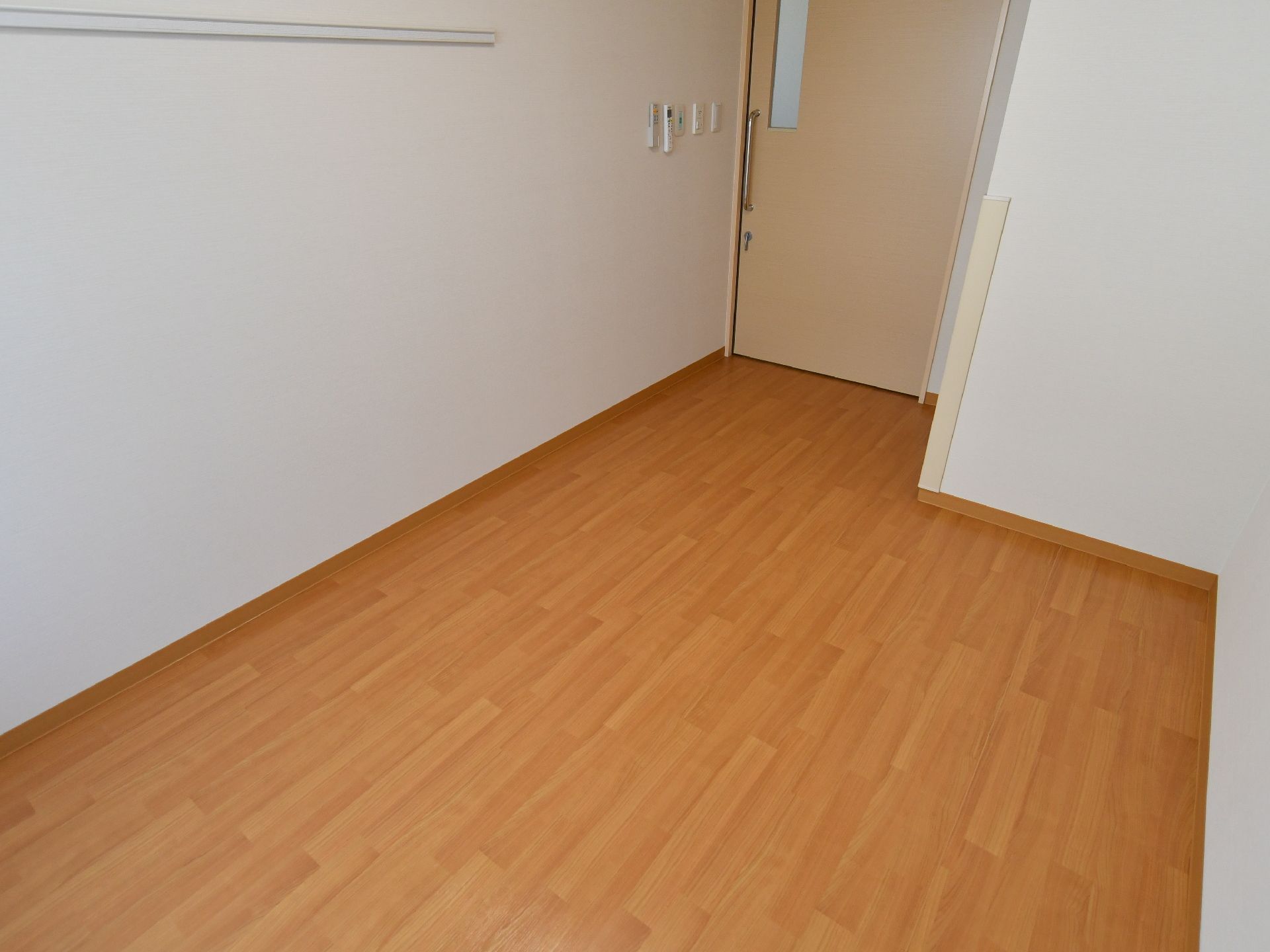 居室の壁は白色で、床は木の色になっている。ドアはベージュ色である。入口付近の壁に、各種リモコンが取り付けられている。