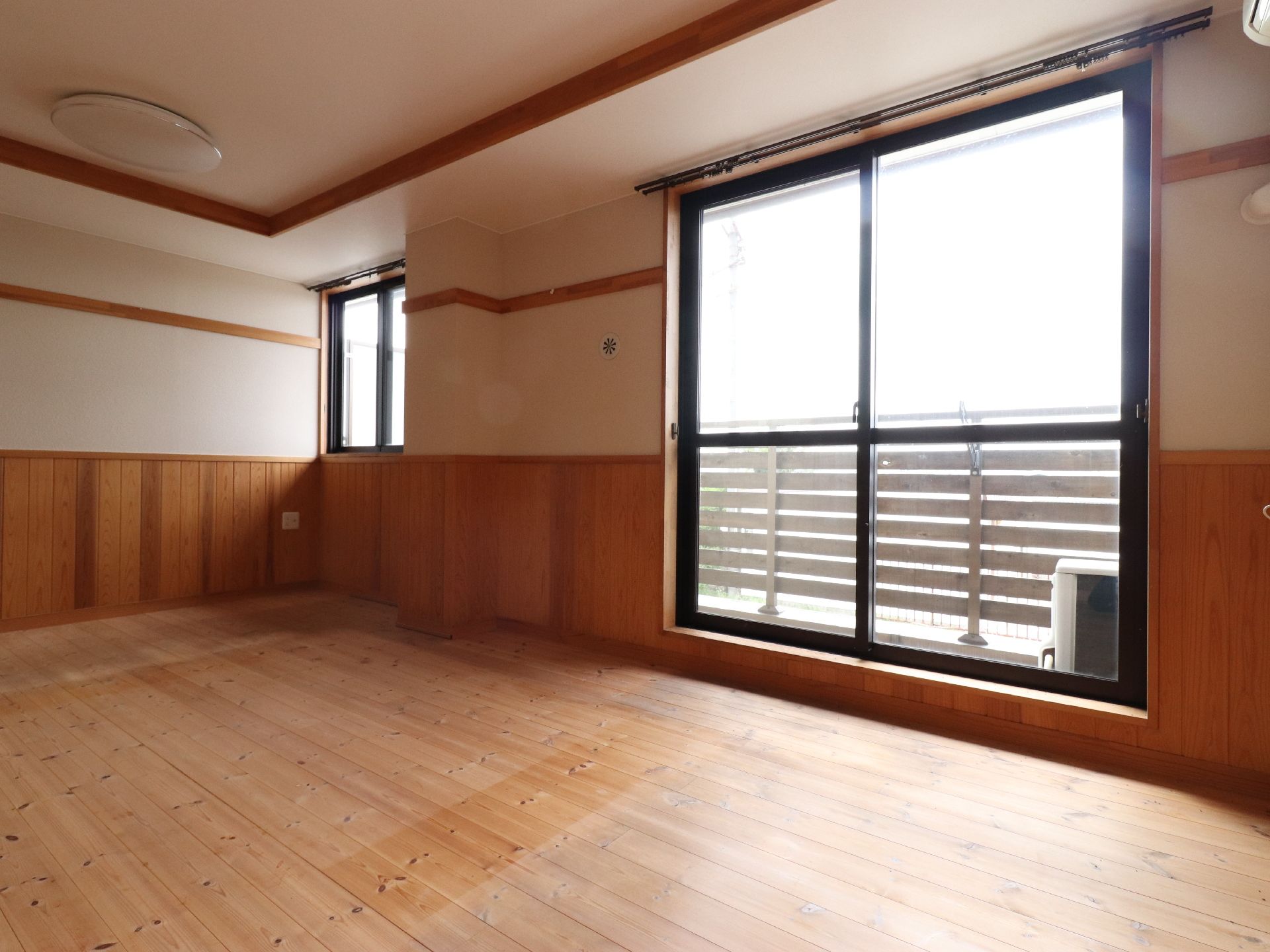 画像の中央には掃き出し窓が設置されており、奥にはベランダの柵がみえている。柵の手前には、乾期で必要な機器が置かれてある。