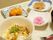 親子丼をメインに小鉢が添えられている。デザートのフルーツの柿は食べやすい大きさに切って盛り付けている。手前にお箸とフォークを置いている。