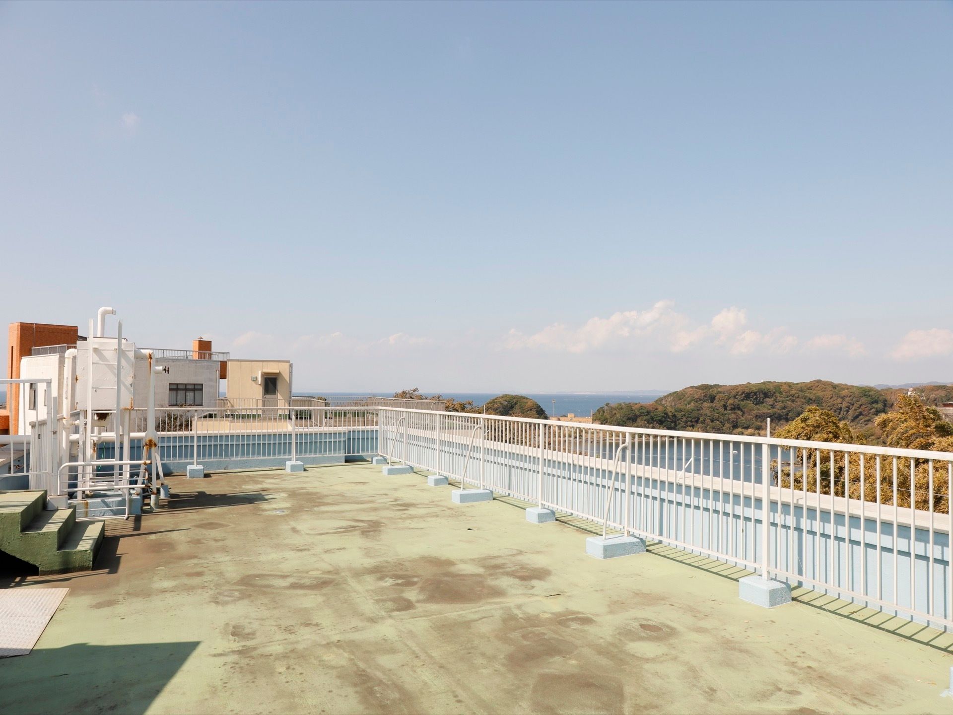 屋上からは、湾と緑豊かな風景を一望できる。コンクリートの床面に、白い囲いと縦格子のフェンスを設置している。