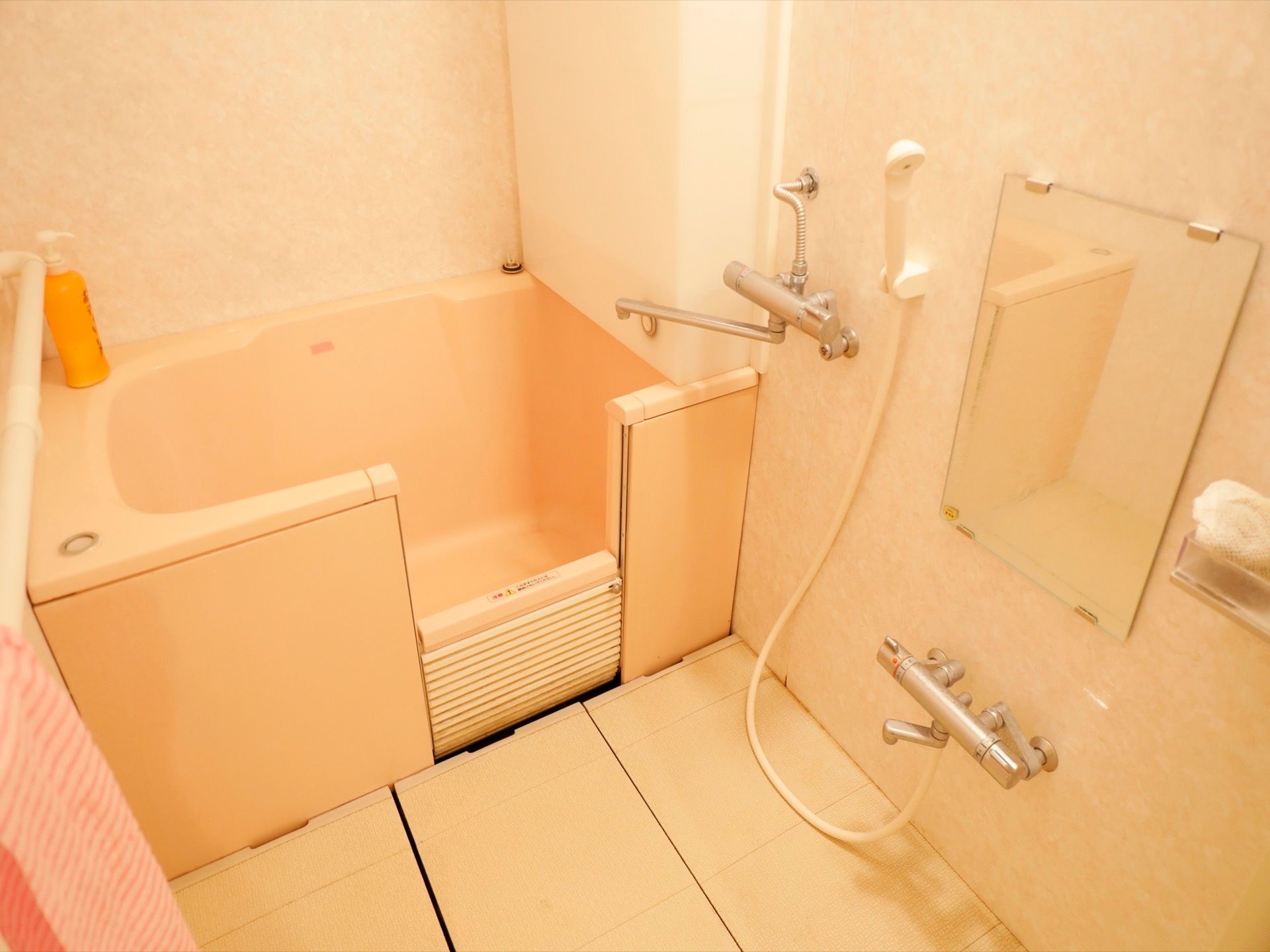 お一人がゆっくりと湯船に浸かれる広さの浴槽を備えた浴室である。側面の一部が上下に開くようになっている。