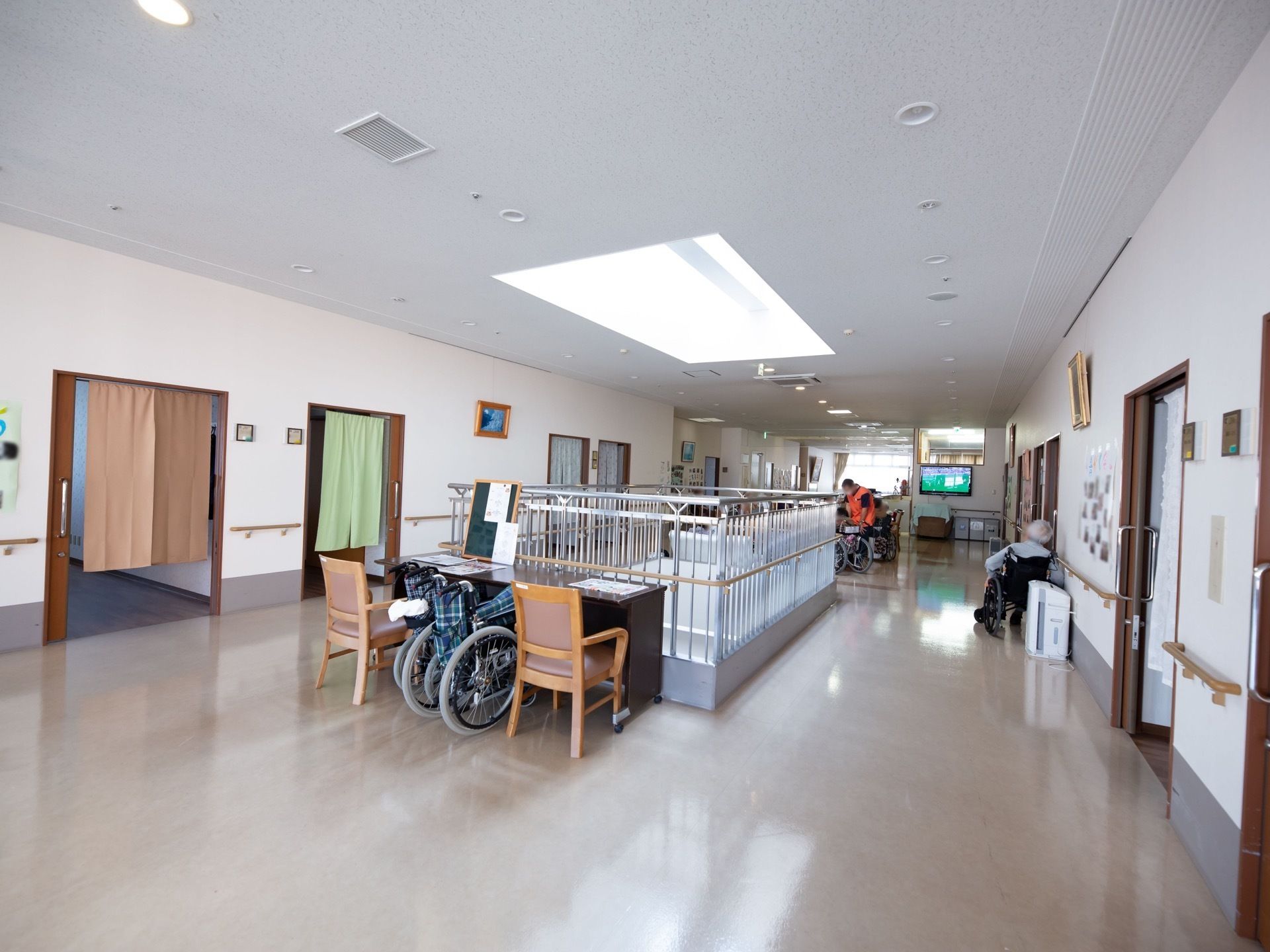 廊下はとても幅が広い。中央部には、吹き抜けがあり、天窓から光が入っている。居室の入口には色違いののれんがかかっている。