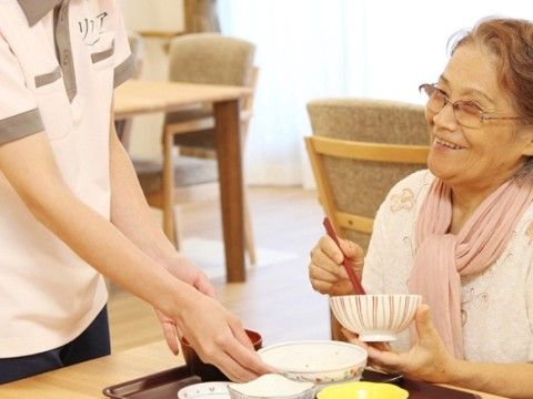 提供された食事を笑顔で楽しんでいる女性利用者の写真