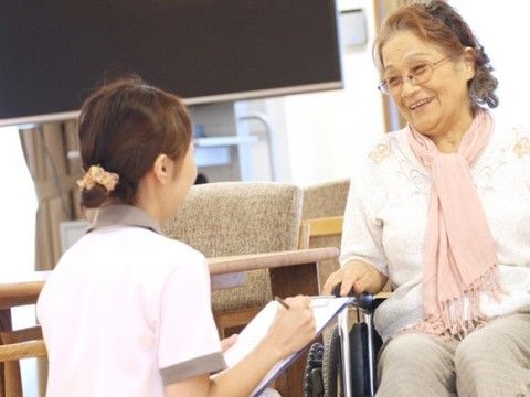施設スタッフと笑顔で会話をしている女性利用者の写真