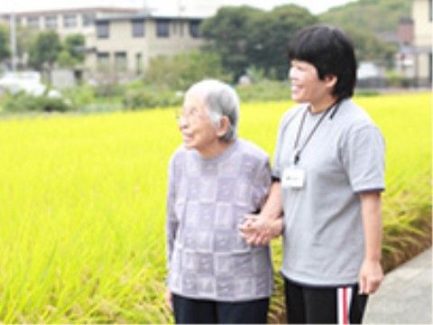 田んぼの傍を散歩する高齢者と介助スタッフ