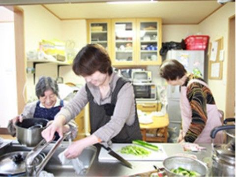 キッチンで調理をする高齢者とスタッフ
