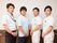 室内で撮影された写真である。スーツを着た男性や介護服を着た４人のスタッフが、手を前に揃えて並んで写っている。