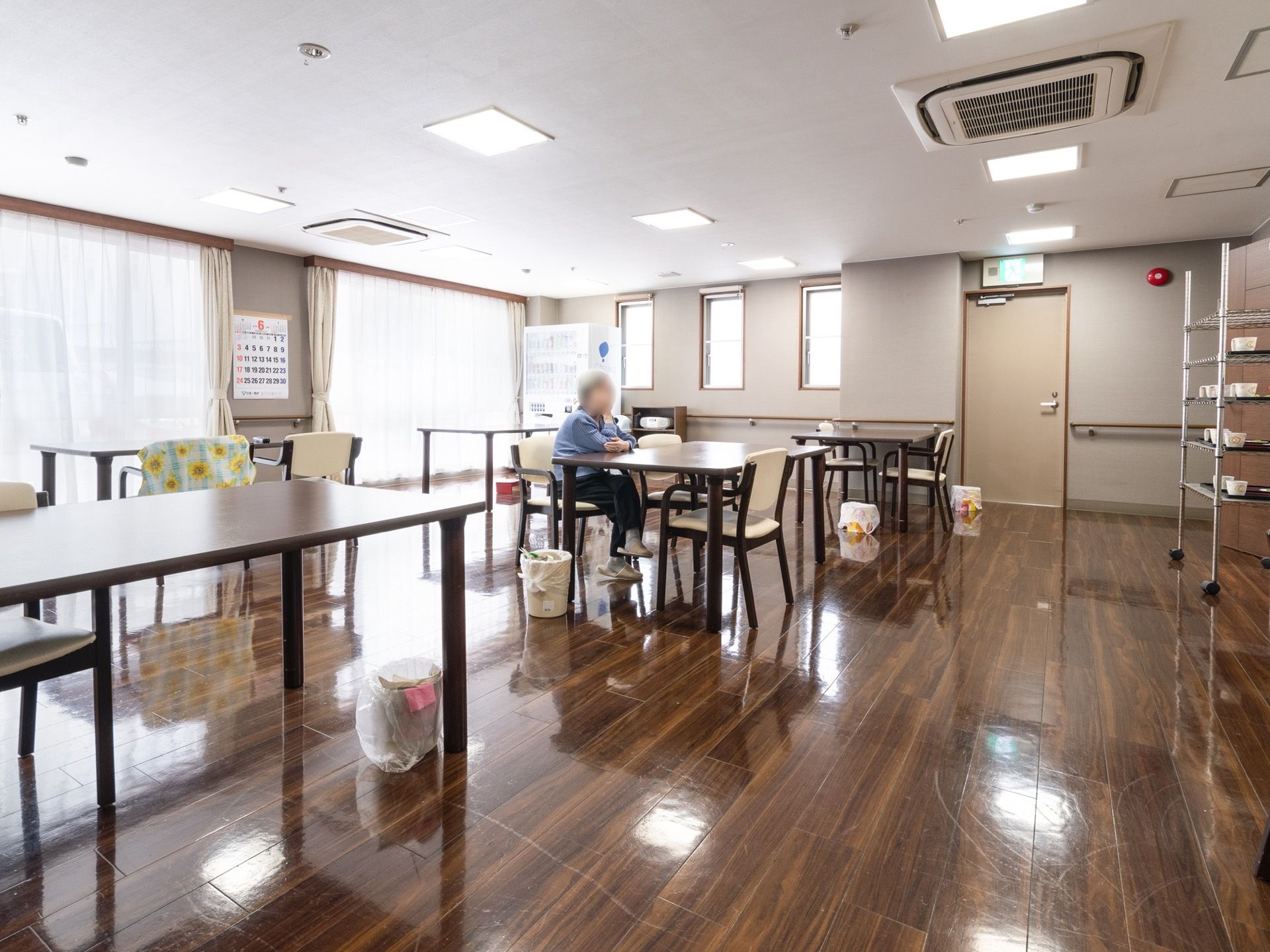 １階にあるリビング兼共同食堂。床のフローリングの材質は光沢がある。各テーブル脇にゴミ箱が用意されている。