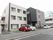 ３階建ての建物の外観。正面玄関口の上から張り出した薄いひさしが非常に広く、歩道のすぐ手前まで伸びている。