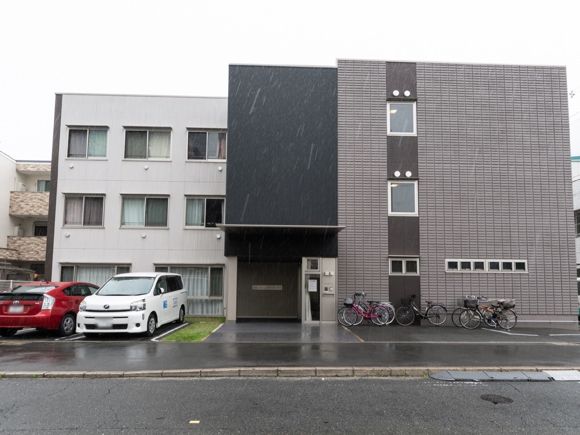 施設の建物の正面玄関側を道路から見た様子。敷地内には駐車場のほかに自転車用の駐輪場も用意されている。