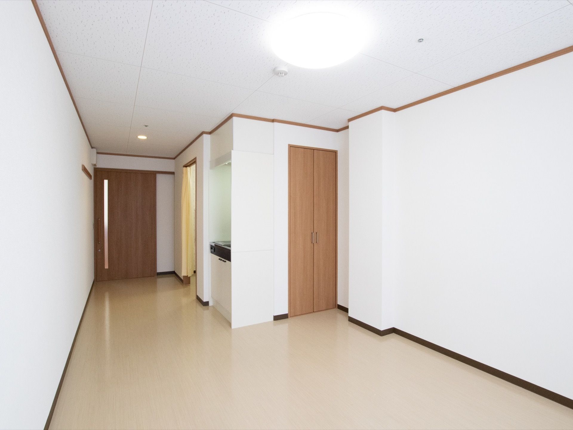居室はバリアフリーになっており、ミニキッチンやクローゼットが備えられている。トイレの出入口には、黄色いカーテンが掛けられている。