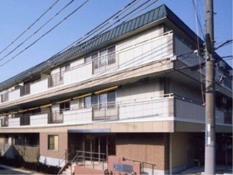 ベージュと白をベースにしたベランダ付き3階建ての施設外観