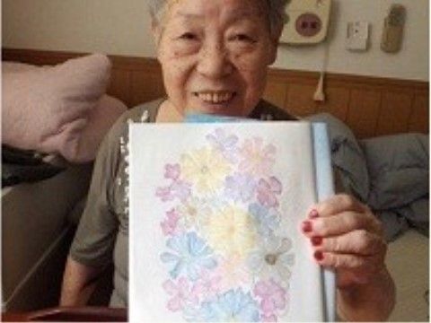 レクリエーションで描かれた絵を見せてくださる利用者様の写真