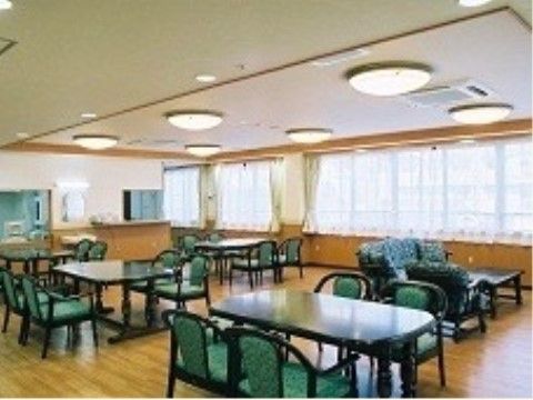グリーンベースのテーブルとイスが並べられた広々とした食堂