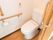 縦横1つずつの手すりが壁に設置された個室トイレで、ナースコールも取りつけられている。手すりの下にペーパーホルダーがある。