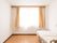 窓が広くて明るい部屋である。天井、壁は白で統一されている。床はフローリングとなっている。壁際に介護用ベッドが置かれている。