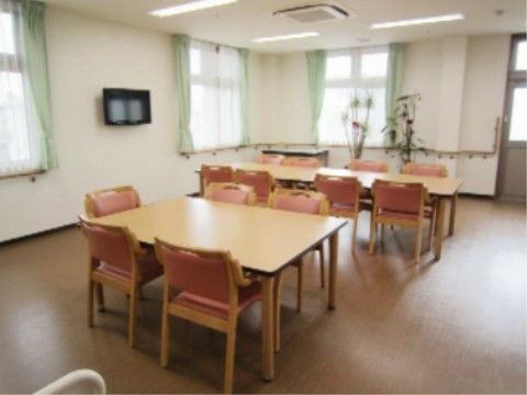ピンクの椅子とミント色のカーテンが印象的などこか可愛さのあるリビングルーム。入り口付近には植物が飾られ手すりも設置されている。