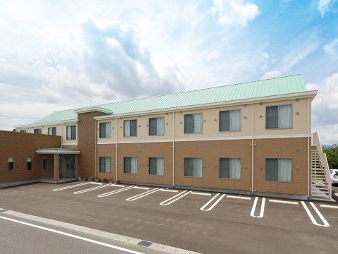 建物手前に駐車スペースが7台以上確保された2階建ての施設外観