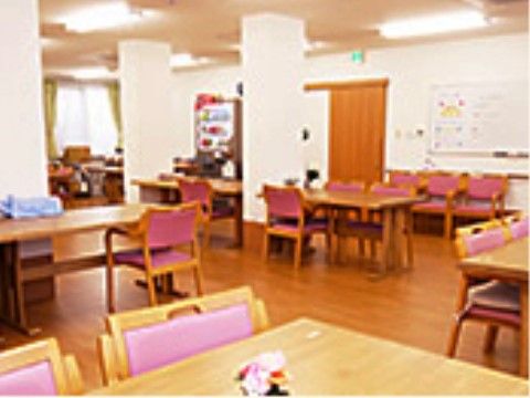 共有スペースにはピンクの椅子が並んだテーブルセットが置かれている。入口横に自動販売機が用意されている。