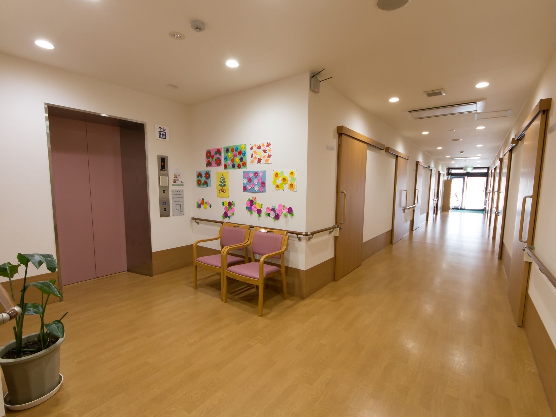 幅を広く取った廊下である。空間にゆとりを持たせたエレベーターホールが設けられている。壁に沿って手すりが備えつけられている。