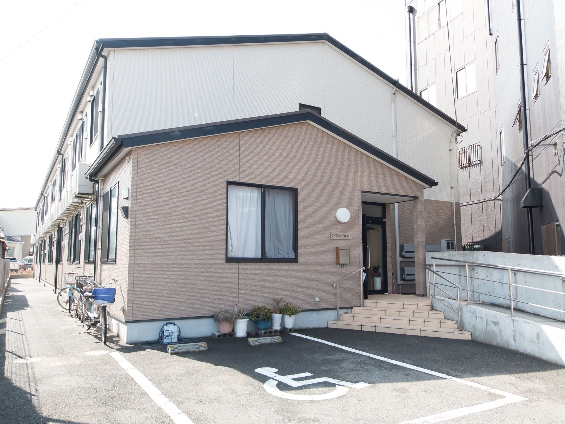 施設はアパート風の２階建ての建物である。手すりが設置された階段とスロープがエントランスに設けられている。