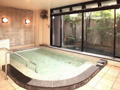 壁におしゃれな丸形の浴室照明が備え付けられた浴室。外には緑ある露天風呂が備え付けられ、一日の疲れを癒してくれる。
