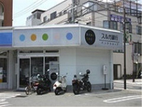 施設から歩いて数分のところに銀行がある。建物前に自転車やバイクが停められている。そばには駐車場もある。
