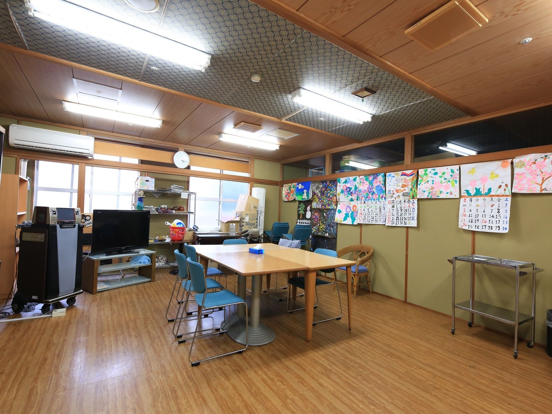 室内は天井が高く広々としている。大きなテーブルの周りに椅子が置かれている。工作やカラオケなど趣味の活動に利用されるスペースである。