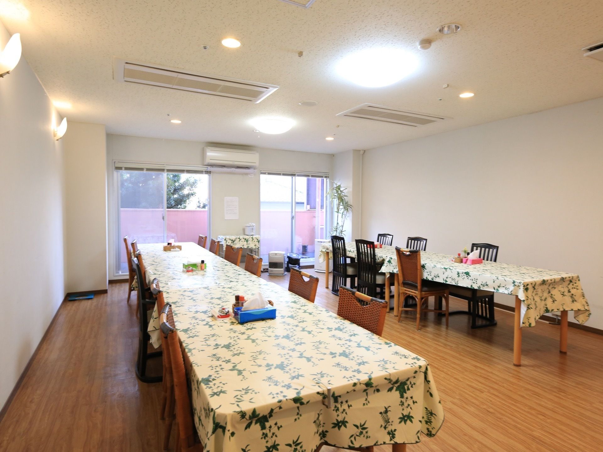広々として日当たりの良い室内に、テーブルが２列に並べて配置されている。花柄の可憐なテーブルクロスがかけられ、室内に華やかさを添えている。