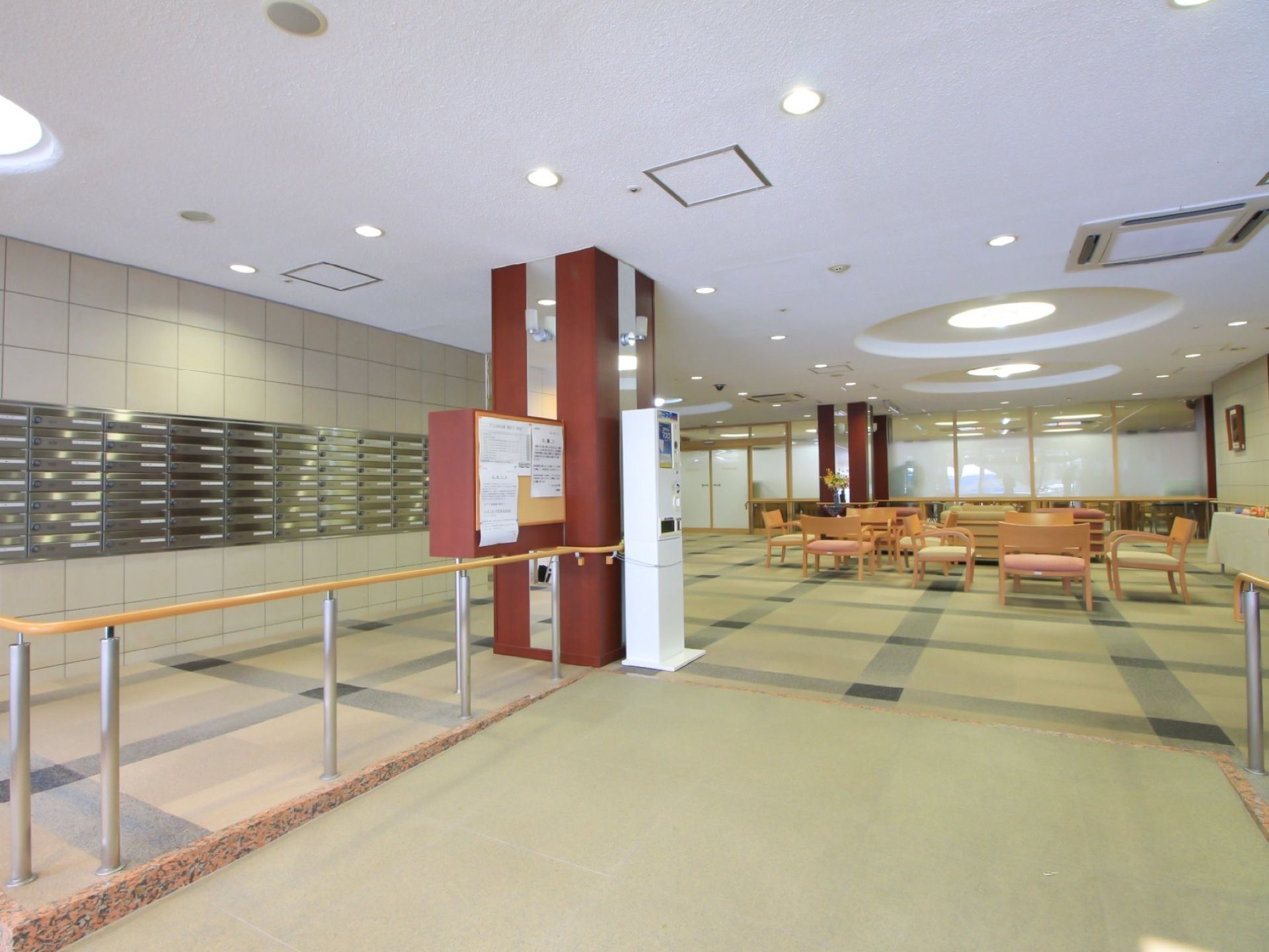 幅の広いスロープの向こうに、たくさんの椅子が並んだロビーがある。ずらりと並んだ郵便受けから、施設の規模が伺える。