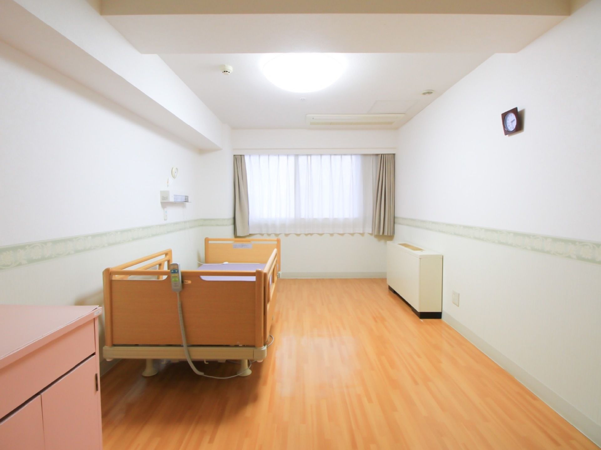 白い壁とフローリングの明るい介護専用居室には、リモコン操作ができる介護用ベッドが設置してある。転落防止の柵があるため、安全だ。