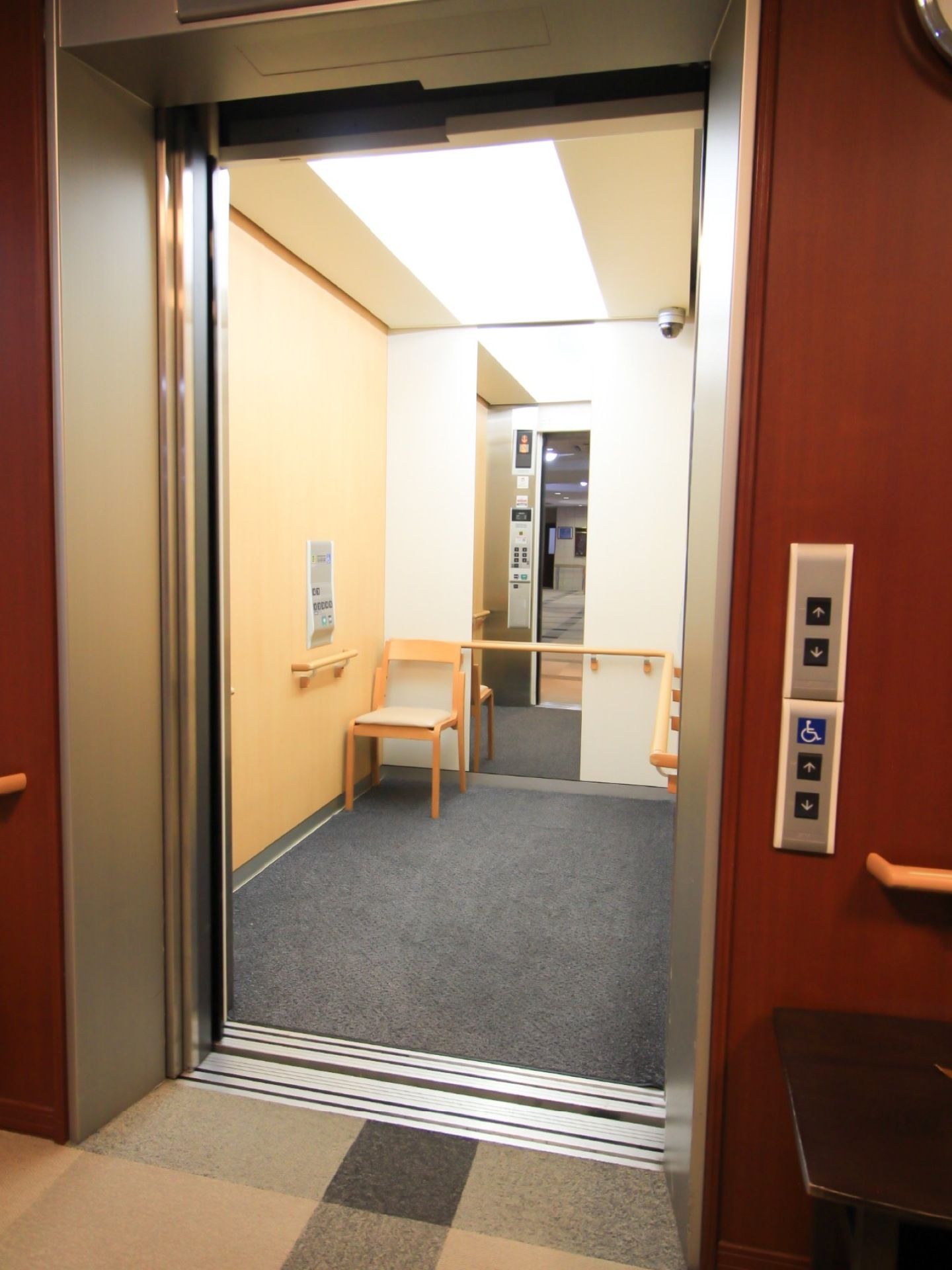 奥行きのあるエレベーター内部には、足腰の弱い方のために椅子が用意してある。鏡が設置してあり、車椅子をご利用の方が後ろを確認しやすい。