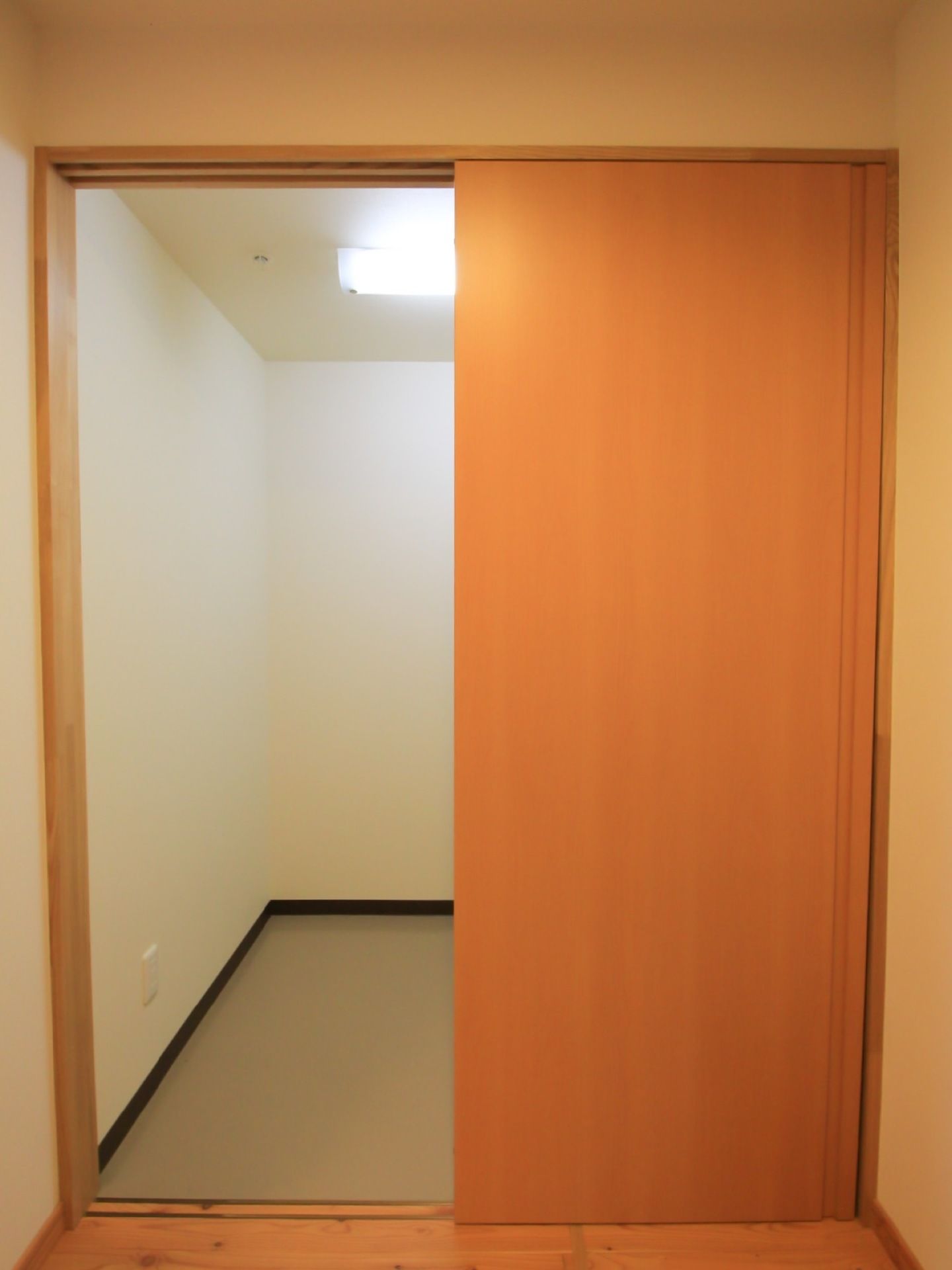 フローリングの居室の一角に、木目調の引き戸が付いている。戸の向こうは、照明の付いた明るい小部屋になっている。