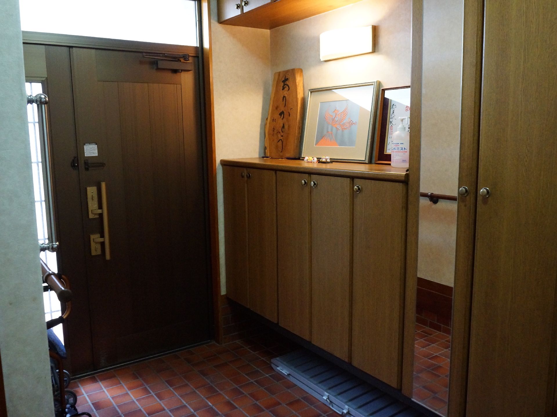 玄関には縦に長い鏡と、縦向きと横向きの手すりが設置されている。足腰に負担が掛かりすぎないよう、靴の脱ぎ履きができる。