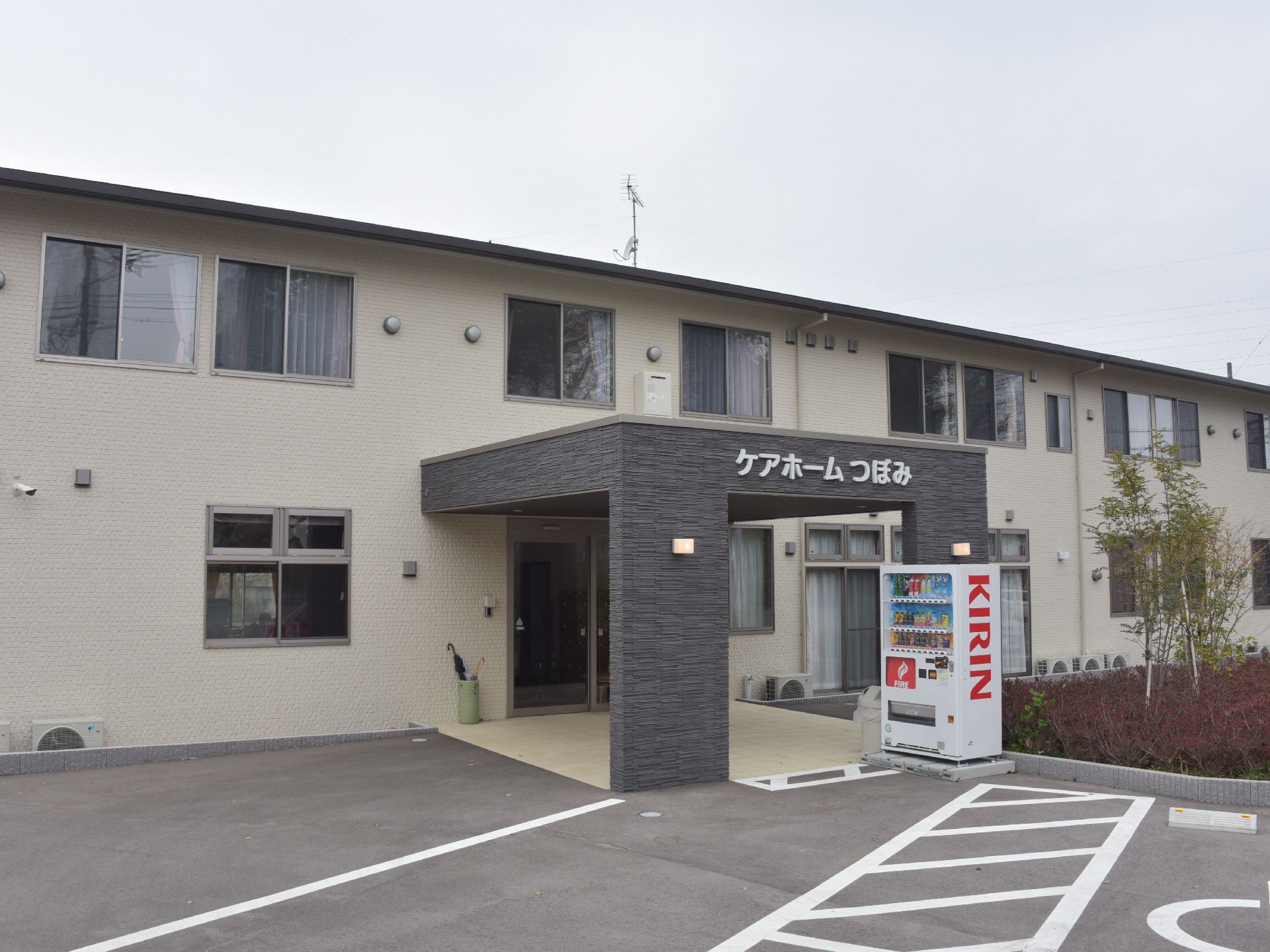 建物は2階建てとなっており、駐車場と入り口には段差が無く、バリアフリーとなっている。また、外には自動販売機が設置されている。