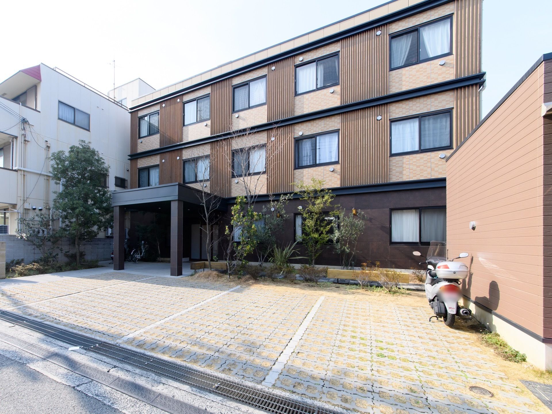 木質の外壁が和モダンな外観である。ホテルのような雰囲気の建物と、木々が植えられたエクステリアは洗練されたデザインである。