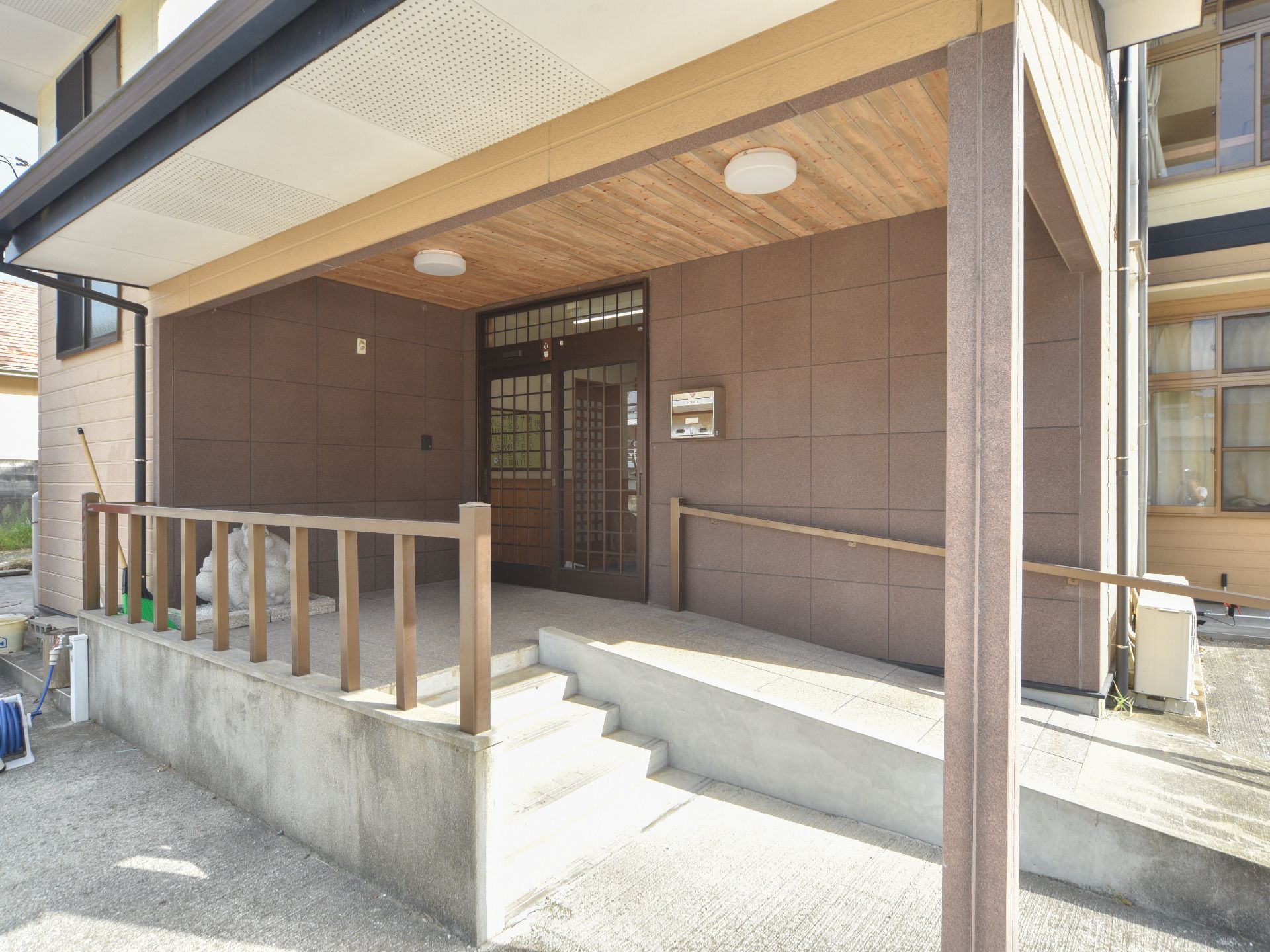 入口までには、4段の階段を使うか、スロープを渡ってたどり着くことができる。どちらも手すりには、無垢な木材が用いられている。