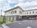 駐車場の入り口には、施設の看板が外の道路から見えるよう立っている。建物の入り口付近には雨をしのげるサッシが付いている。